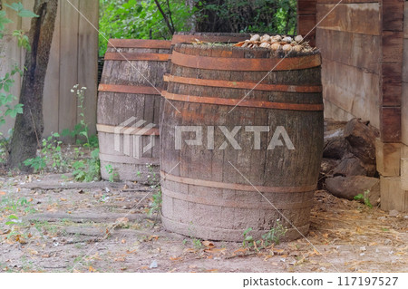 Old barrel with a green garden background. Vintage rusty barrels. Old barrel with a green garden background. Vintage rusty barrels. 117197527