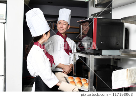 Smiling Asian man and woman making bread in the kitchen 117198068