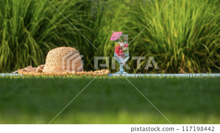Straw hat and glass of cool drink with fruit and pink umbrella beside the pool Straw hat and glass of cool drink with fruit and pink umbrella beside the pool 117198442