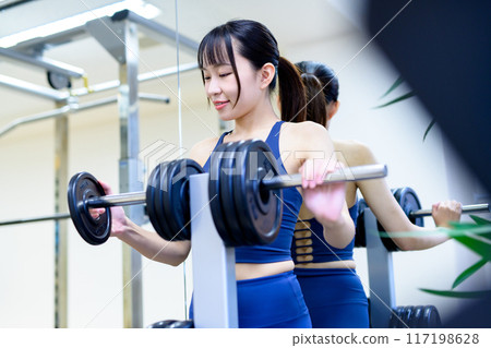 Women working out at the gym, barbell plates, weight selection, women doing muscle training, workout 117198628