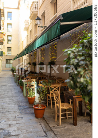 Outdoor street cafe tables ready for service. Empty cafe terrace with wooden tables and chairs, morning time. Food concept 117200668