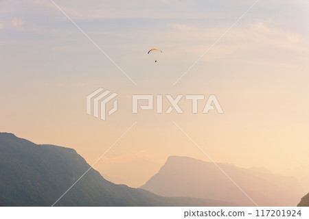 Paraglider in the air fly over the mountains at summer sunrise. Paraglider in the air fly over the mountains at summer sunrise. 117201924