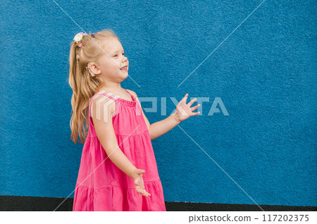 Child girl walks and have fun outdoor with cochlear implant on the head. Hearing aid and treatment concept. Copy space. Inclusion 117202375