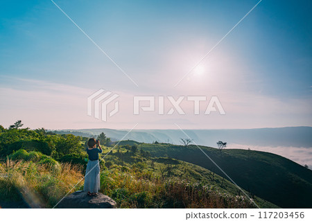 Woman looking at the view from the top of a mountain 117203456