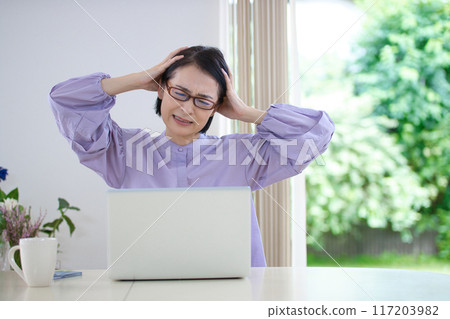 客廳裡，中年婦女抱著頭看電腦 117203982