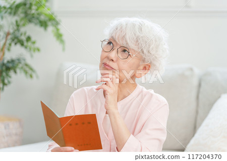 Senior female looking at pension book Senior female looking at pension book 117204370