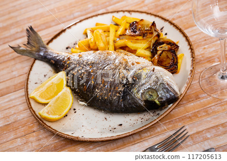 Baked dorada with french fries, fried onions and lemon 117205613