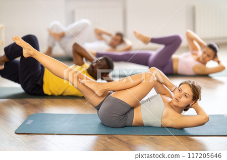 Group of multinational people doing exercises for press during group class in fitness studio 117205646