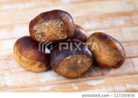 Unpeeled edible sweet chestnuts on wooden background Unpeeled edible sweet chestnuts on wooden background 117205656