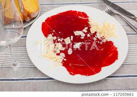 Carpaccio and cheese served on plate. Dish made of raw beef meat closeup 117205661