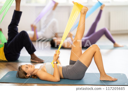 Multinational group of people with working out with rubber bands lying on your back in gym Multinational group of people with working out with rubber bands lying on your back in gym 117205685