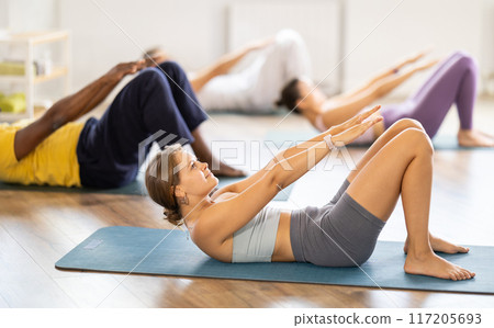 Young woman with multinational athletes group raise and lower torso 117205693