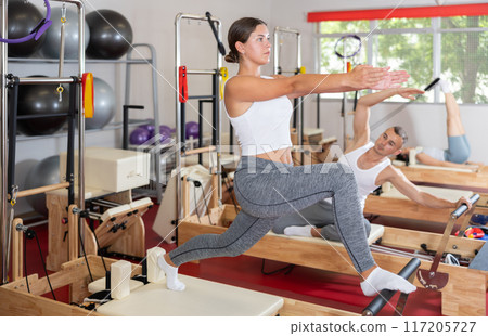 Young woman doing stretching on pilates reformer 117205727