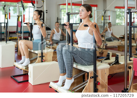 Young girl training her legs in seated position on combo chair Young girl training her legs in seated position on combo chair 117205729