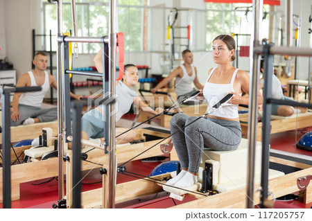 Young woman training her arms using straps Young woman training her arms using straps 117205757