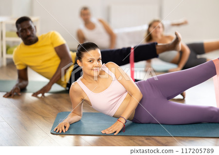 Group of multinational people training leg muscles using resistance bands during Pilates studio Group of multinational people training leg muscles using resistance bands during Pilates studio 117205789