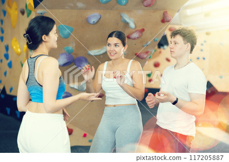 Sports women and man are actively discussing the successes and mistakes of other athletes on mountaineering simulator Sports women and man are actively discussing the successes and mistakes of other athletes on mountaineering simulator 117205887