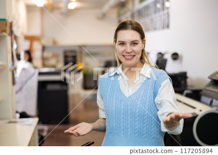 Friendly print shop employee invites customer to come inside 117205894