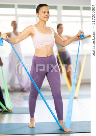 Asian woman using elastic exercise band at group training 117206004