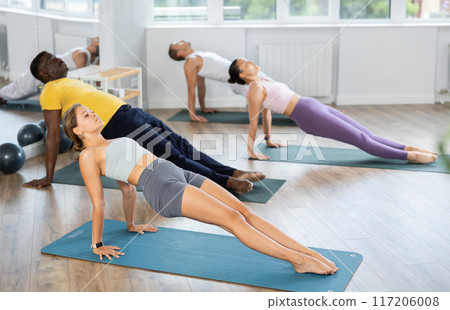 Girl performing Upward Plank Pose during group yoga training Girl performing Upward Plank Pose during group yoga training 117206008