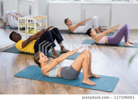 Young woman with multinational athletes group raise and lower torso 117206061