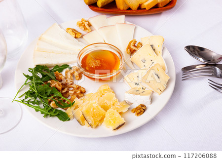 Delicious cheese platter with honey, walnuts and arugula 117206088