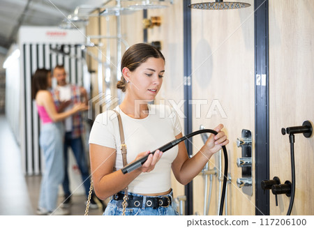 Young woman choosing shower head in store 117206100