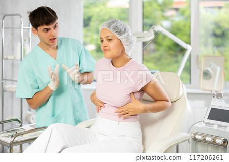 Young male doctor consulting female client on breast augmentation Young male doctor consulting female client on breast augmentation 117206261