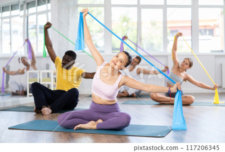 Asian woman exercising with elastic resistance band in group fitness class Asian woman exercising with elastic resistance band in group fitness class 117206345