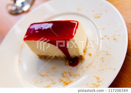 Classic cheesecake served with sweet berry sauce in cafe Classic cheesecake served with sweet berry sauce in cafe 117206384