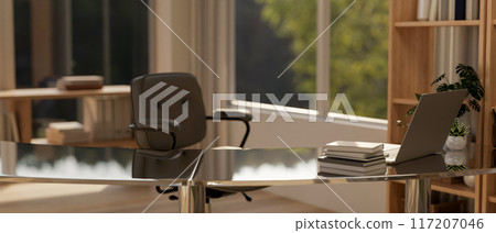 A modern office desk features a laptop, books, and decor plants in a contemporary room. A modern office desk features a laptop, books, and decor plants in a contemporary room. 117207046