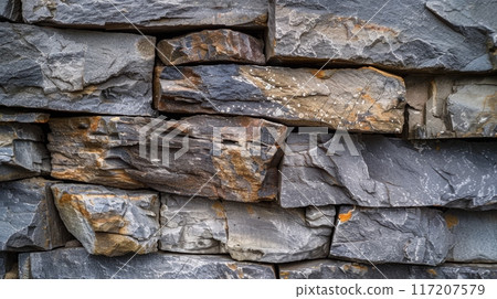 Close up of a stone wall with rocks stacked on top 117207579