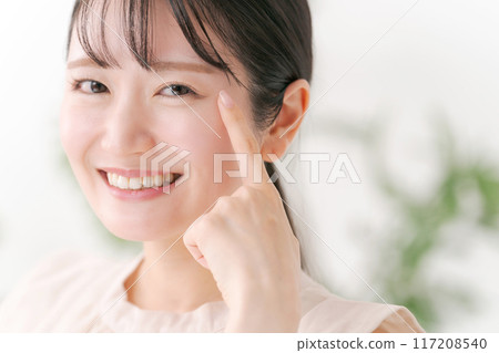 Young woman pointing at eyes 117208540