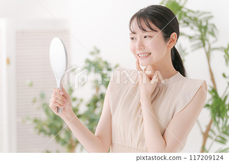 Woman checking her teeth with a mirror Woman checking her teeth with a mirror 117209124