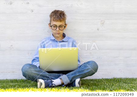 A boy using a laptop outdoors A boy using a laptop outdoors 117209349