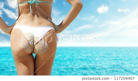 Girl in a bikini standing in the sea on a bright, sunny summer day Girl in a bikini standing in the sea on a bright, sunny summer day 117209407