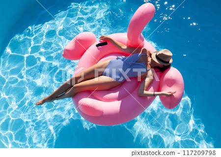 Woman relaxing on pink flamingo inflatable ring Woman relaxing on pink flamingo inflatable ring 117209798