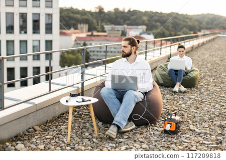 Business people working outdoors on rooftop with laptops Business people working outdoors on rooftop with laptops 117209818