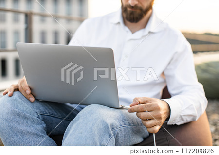 Business man charging laptop on rooftop with portable power station Business man charging laptop on rooftop with portable power station 117209826