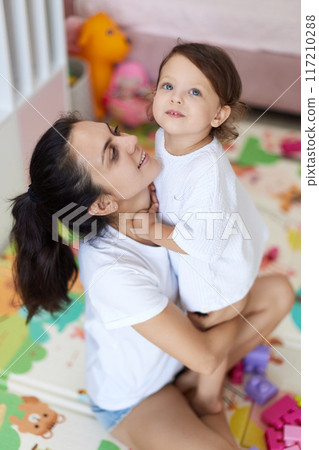happy mother with cute baby girl in white t-shirt having fun together 117210288