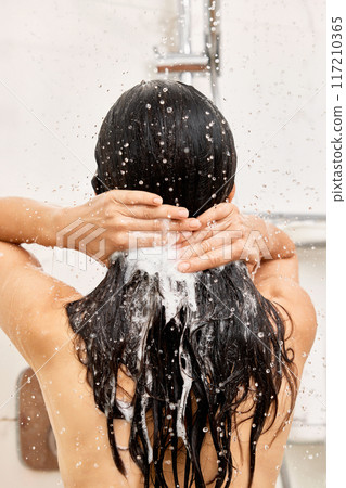 Young woman taking refreshing shower in white modern bathroom. girl washes shampoo out of hair, back view 117210365