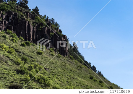 Mountain landscape with green grass and blue sky in the background. Wildlife of Eastern Siberia. Mountain landscape with green grass and blue sky in the background. Wildlife of Eastern Siberia. 117210639