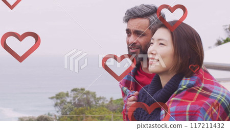 Image of hearts over diverse couple embracing on balcony 117211432