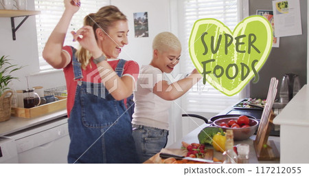 Image of super foods text over diverse female couple cooking at home 117212055