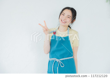 一個穿著圍裙的女人看著她的智慧型手機 117212120