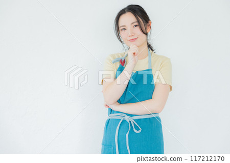 A woman in an apron thinking 117212170