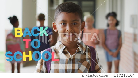 Image of back to school text over happy biracial schoolboy at school 117213164