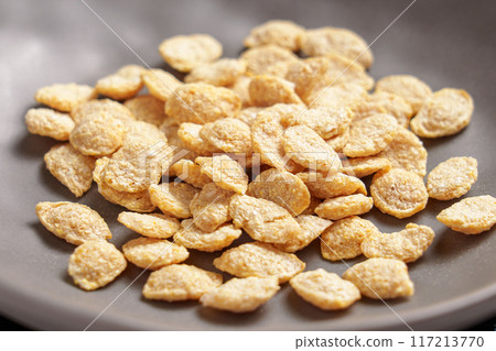Nutritious breakfast cereal flakes fall while cooking in gray bowl. Healthy food ingredient 117213770