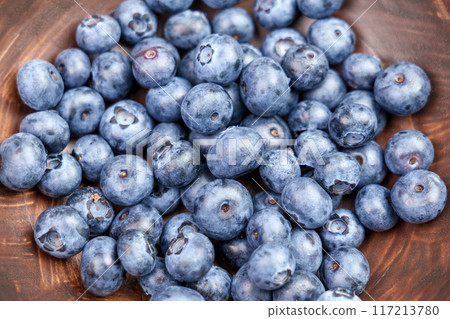 Fresh juicy organic blueberries in an eco-friendly wooden bowl close-up. Top view.  117213780
