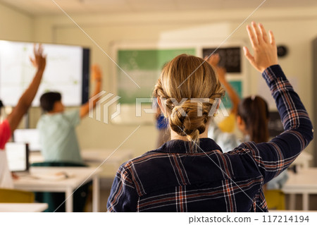 In high school, students raising hands in classroom, actively participating in lesson In high school, students raising hands in classroom, actively participating in lesson 117214194